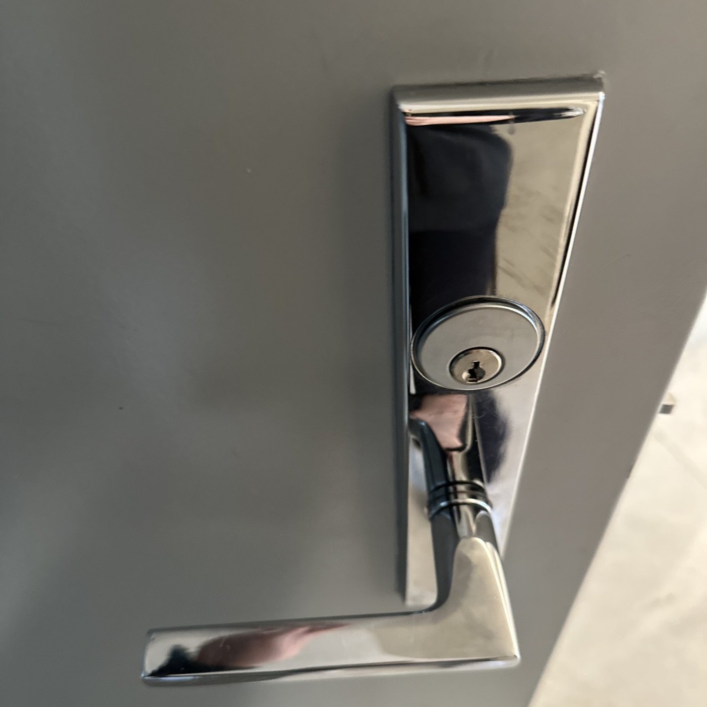 Polished chrome lever lock installed on a grey door, Metro Local Locksmith