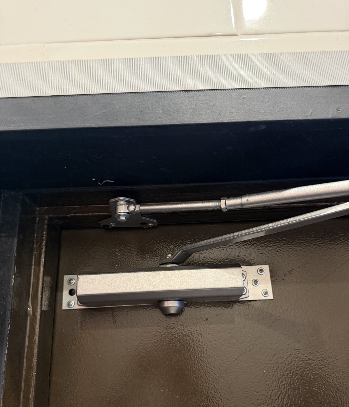 Commercial door closer with a mounting plate, installed by Metro Local Locksmith on the Upper East Side, Manhattan