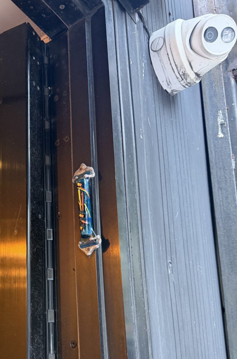 Heavy-duty continuous hinge on an aluminum storefront door frame with a security camera above, installed by Metro Local Locksmith on the Upper East Side, Manhattan