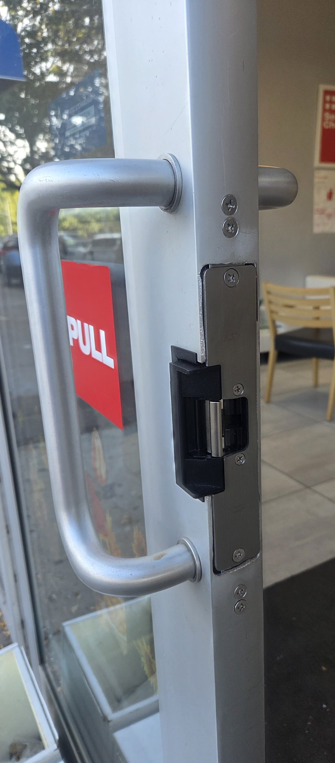 Electric strike set into an aluminum door stile next to a pull handle for keyless access control, Bronx, NYC