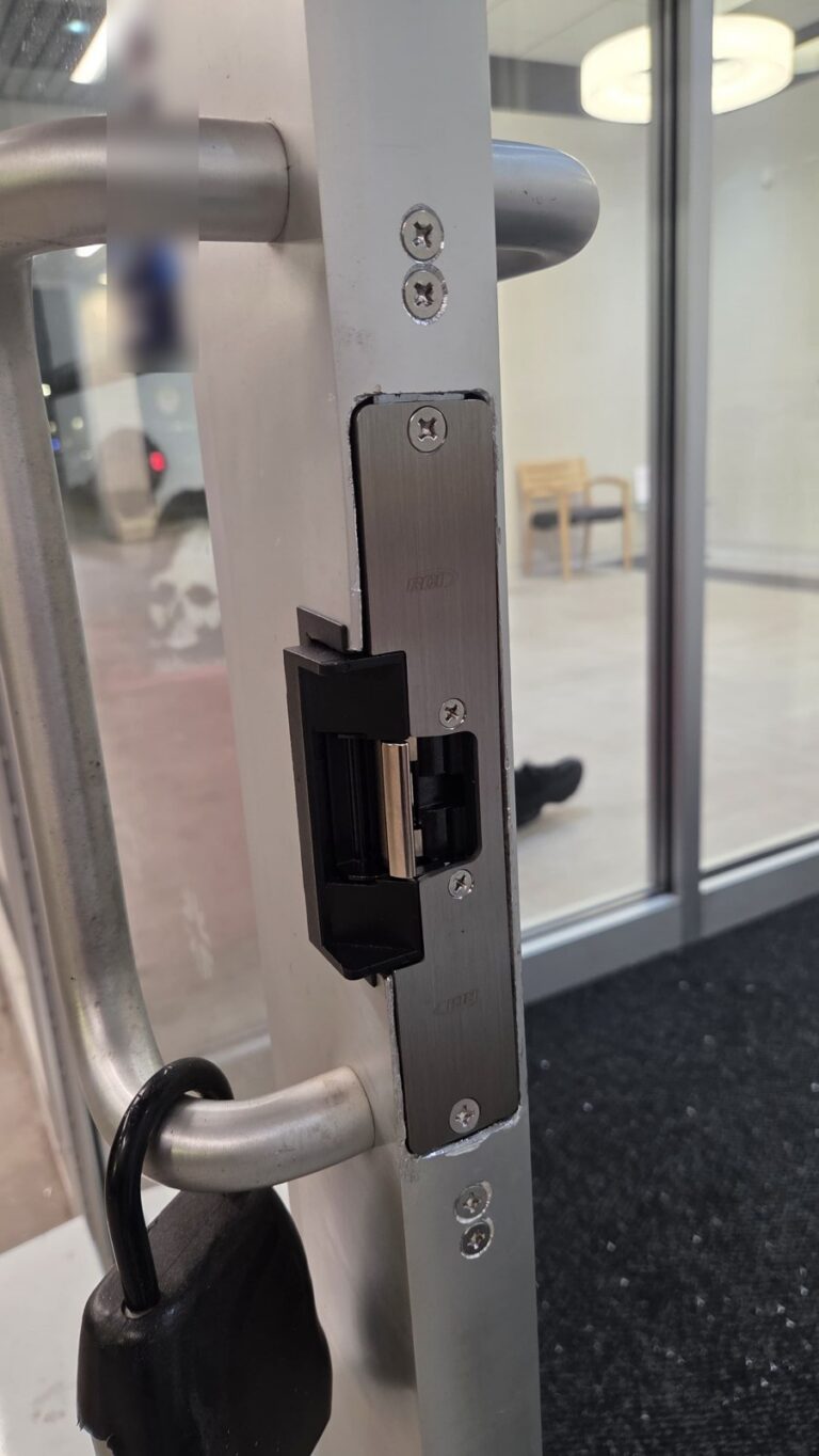 Close-up of an electric strike releasing the latch on a glass storefront door, installed by Metro Local Locksmith in the Bronx, NYC