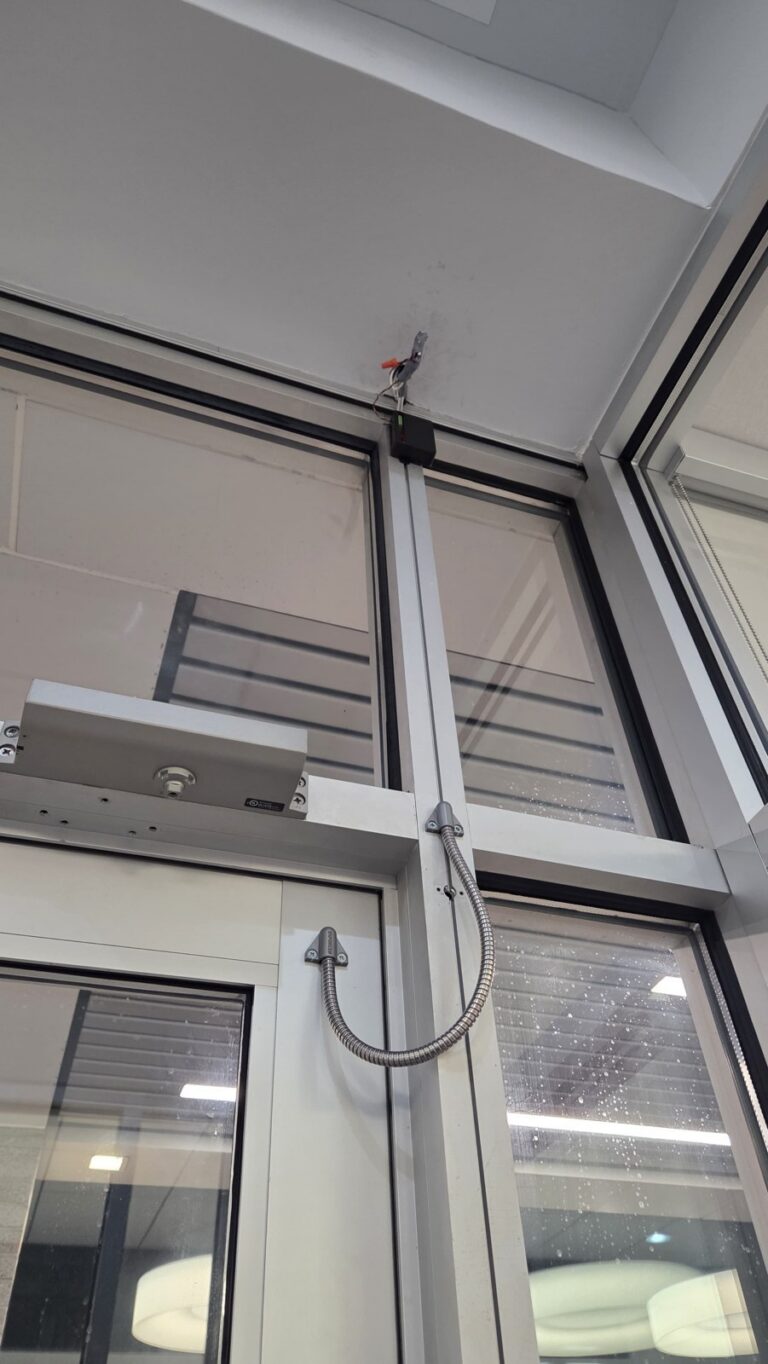 Maglock on a storefront door header with an armored door loop protecting the cable, installed by Metro Local Locksmith in the Bronx, NYC