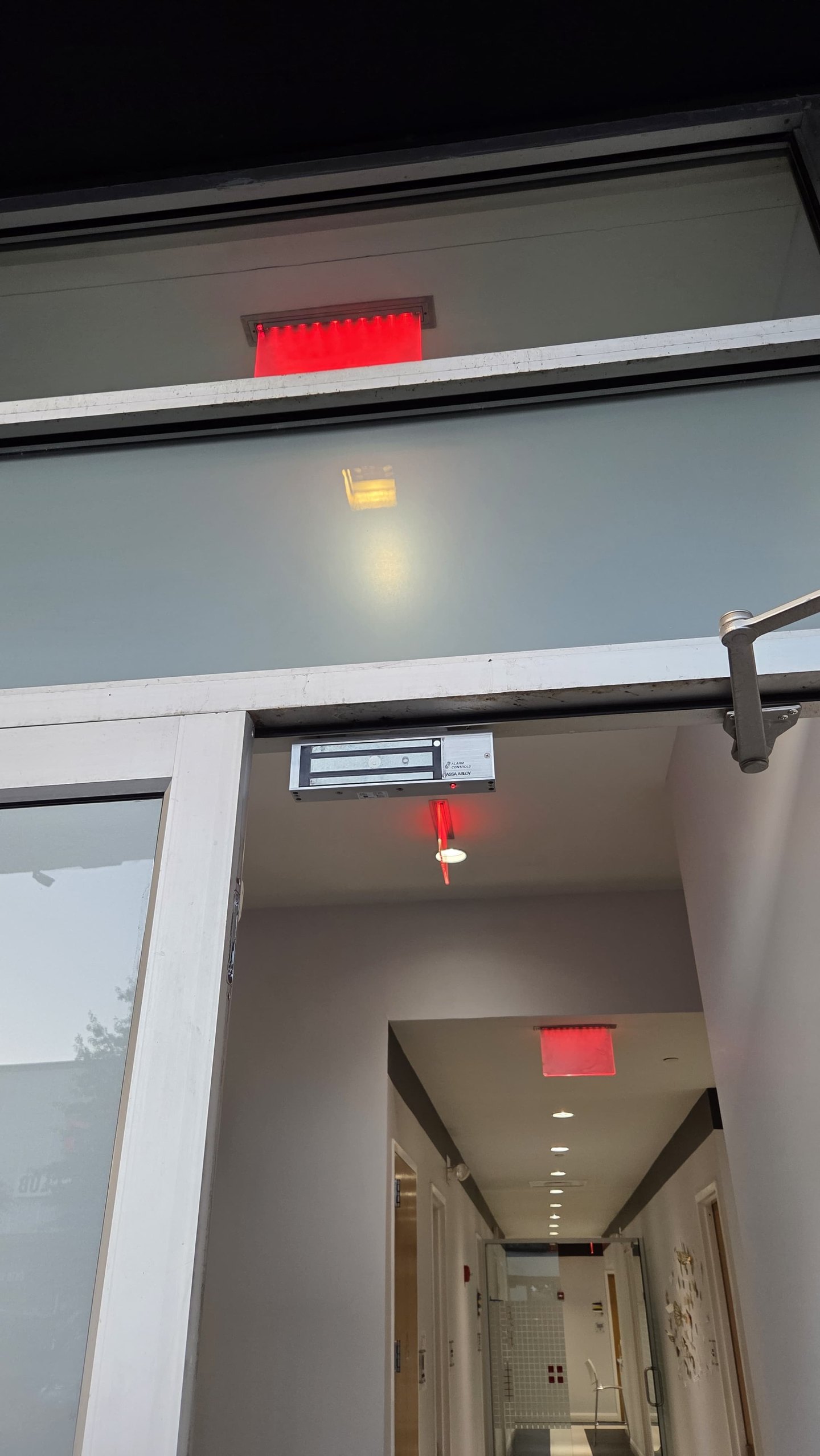 Electromagnetic lock (maglock) mounted on the header over a commercial entry door, Bronx, NYC