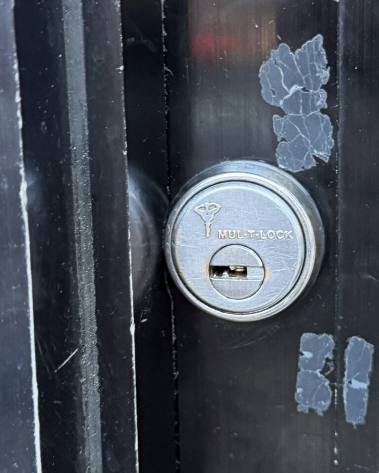 Restricted high-security Mul-T-Lock cylinder on a black aluminum door stile, installed by Metro Local Locksmith on the Upper East Side, Manhattan