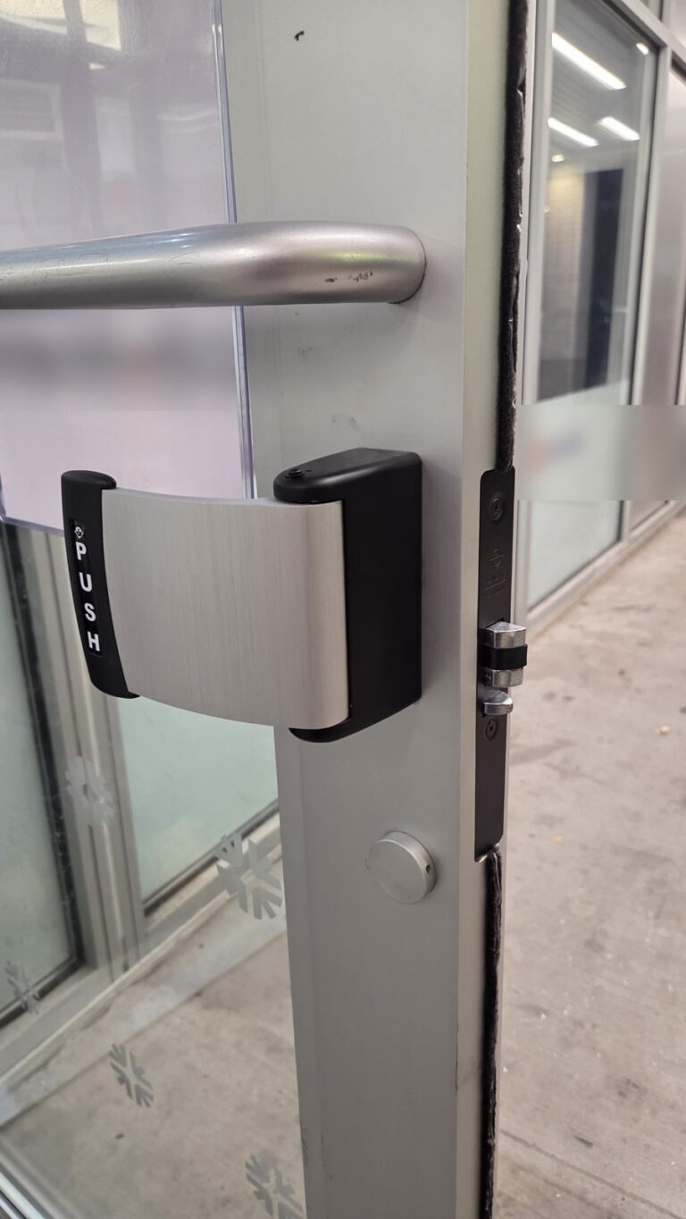 Push-paddle exit device on the inside of a glass storefront door, installed by Metro Local Locksmith in the Bronx, NYC