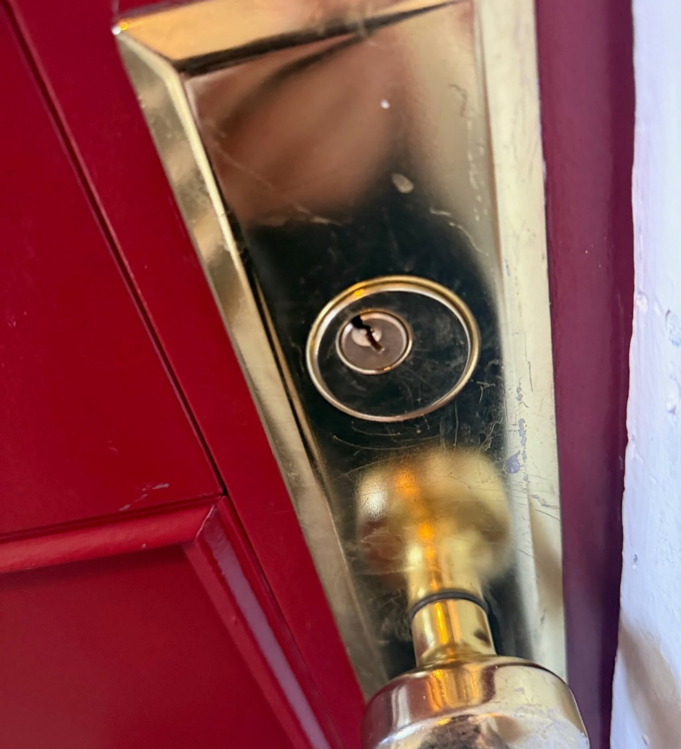 Brass entry lock on residential door - Metro Local Locksmith Polished brass entry lock on a red residential door, installed by Metro Local Locksmith, NYC