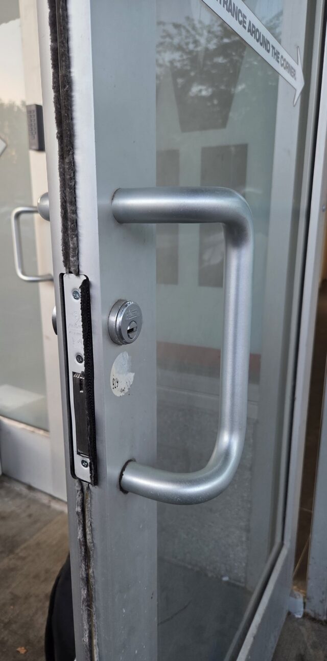Satin pull handle and mortise cylinder on an aluminum storefront door, Bronx, NYC