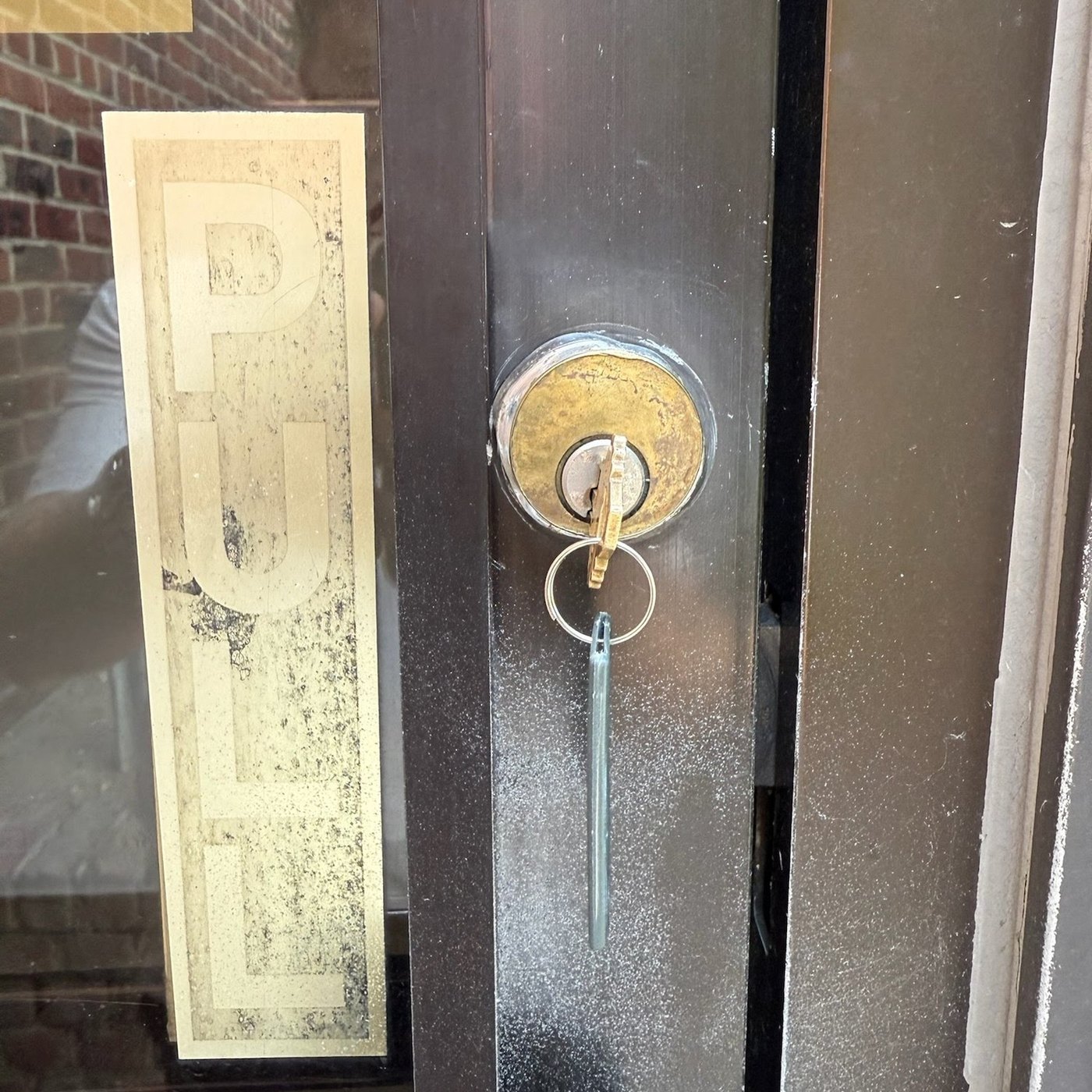 Key in the cylinder lock of a storefront door next to the pull plate, Metro Local Locksmith