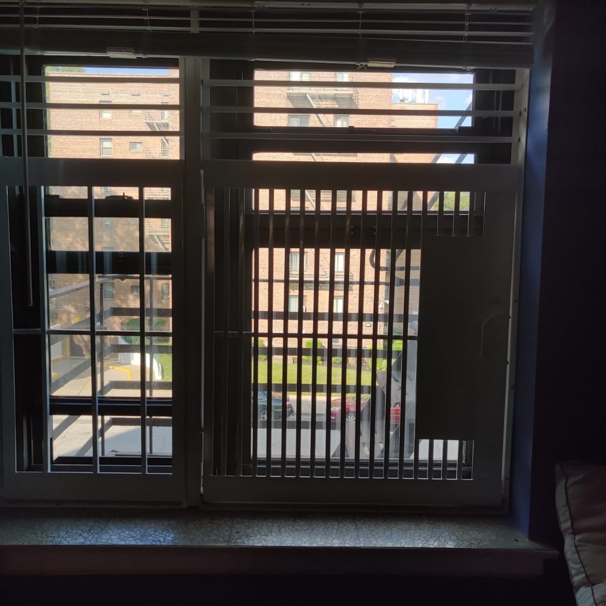 Window gates with fire escape view - Metro Local Locksmith Steel window gates on an apartment window with a fire escape outside, Metro Local Locksmith